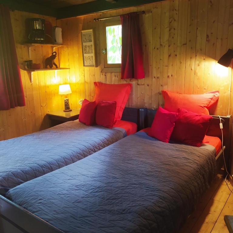 - 2 lits dans une chambre avec des oreillers rouges dans l'établissement CABANE CERISE DANS L'ARBRE Etapeboisee, à Fumay