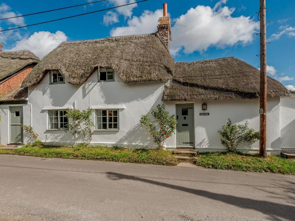 a white house with a thatched roof at Eton Cottage in Farnham