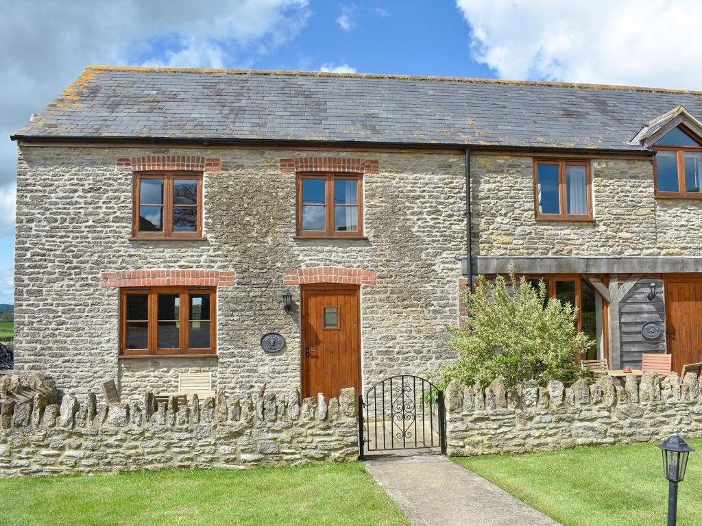 una antigua casa de piedra con una valla de piedra en Jolliffe - Dbbk en Leigh