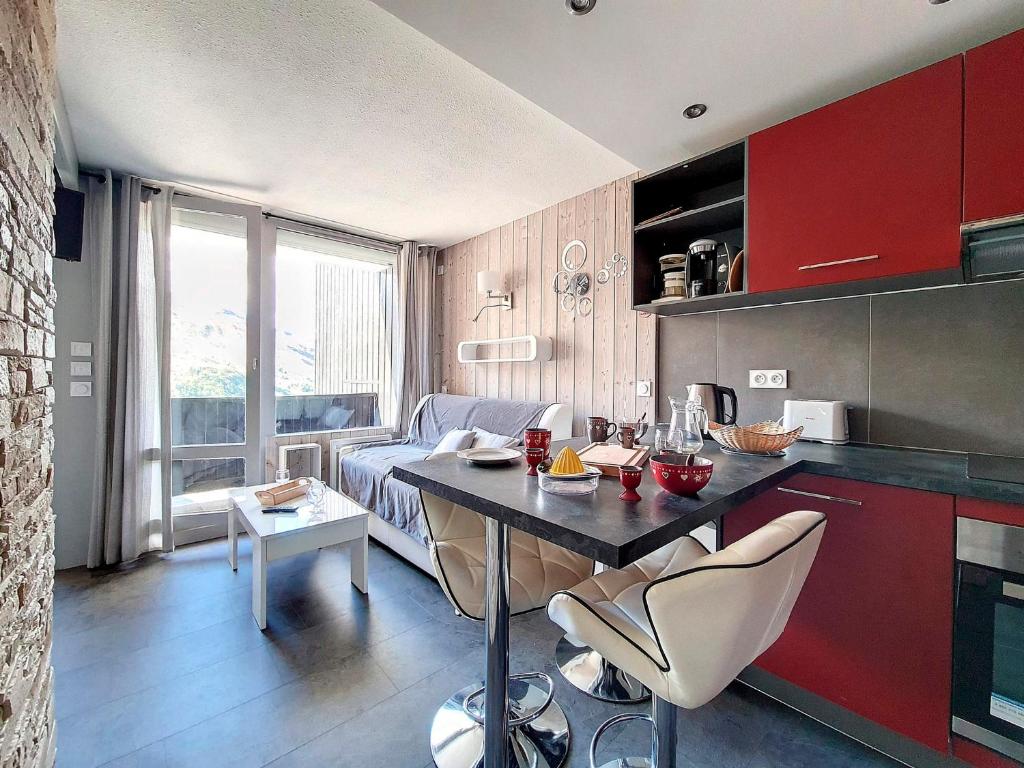 a kitchen and living room with red cabinets and a table at Appartement Les Menuires, 2 pièces, 4 personnes - FR-1-344-896 in Les Menuires