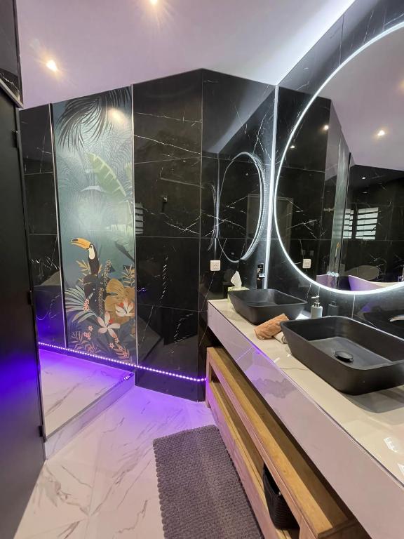 La salle de bains est pourvue de 2 lavabos et d'un grand miroir. dans l'établissement Villa Prana, à La Saline les Bains