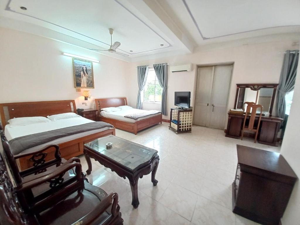 a bedroom with two beds and a coffee table in it at Nhật An Hotel in Ho Chi Minh City