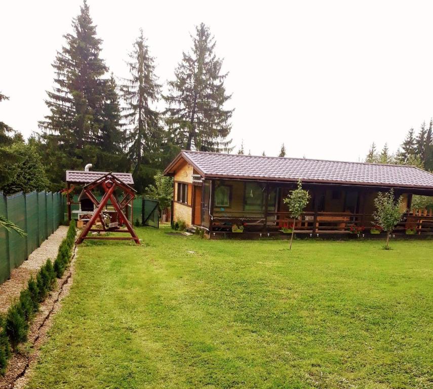 eine Hütte auf einem Feld mit einem Hof mit einem Haus in der Unterkunft Ezüst fenyő vendégház in Borzont