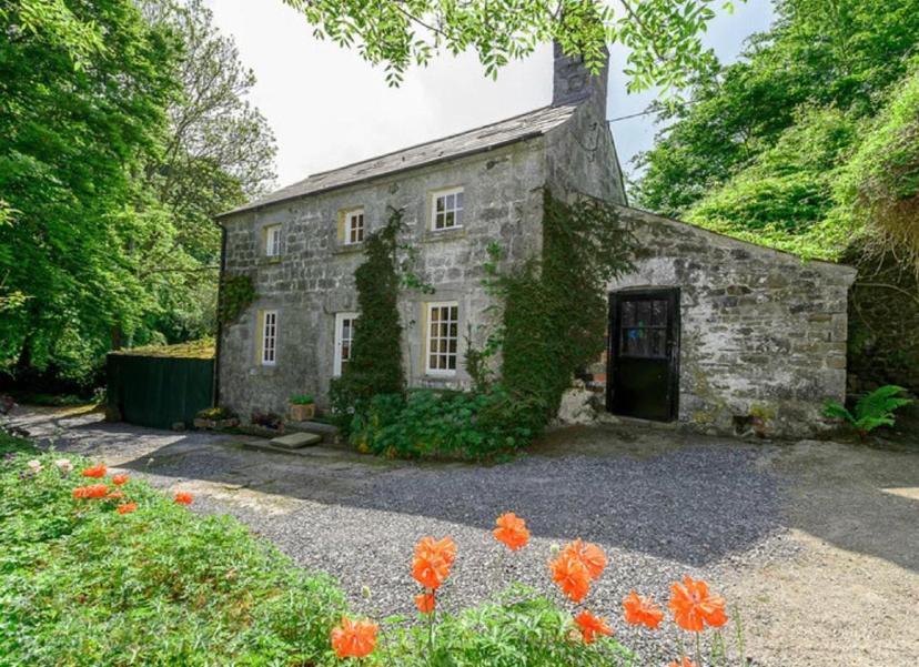 an old stone house with orange flowers in front of it at A magical hideaway overlooking the river Boyne in Donore