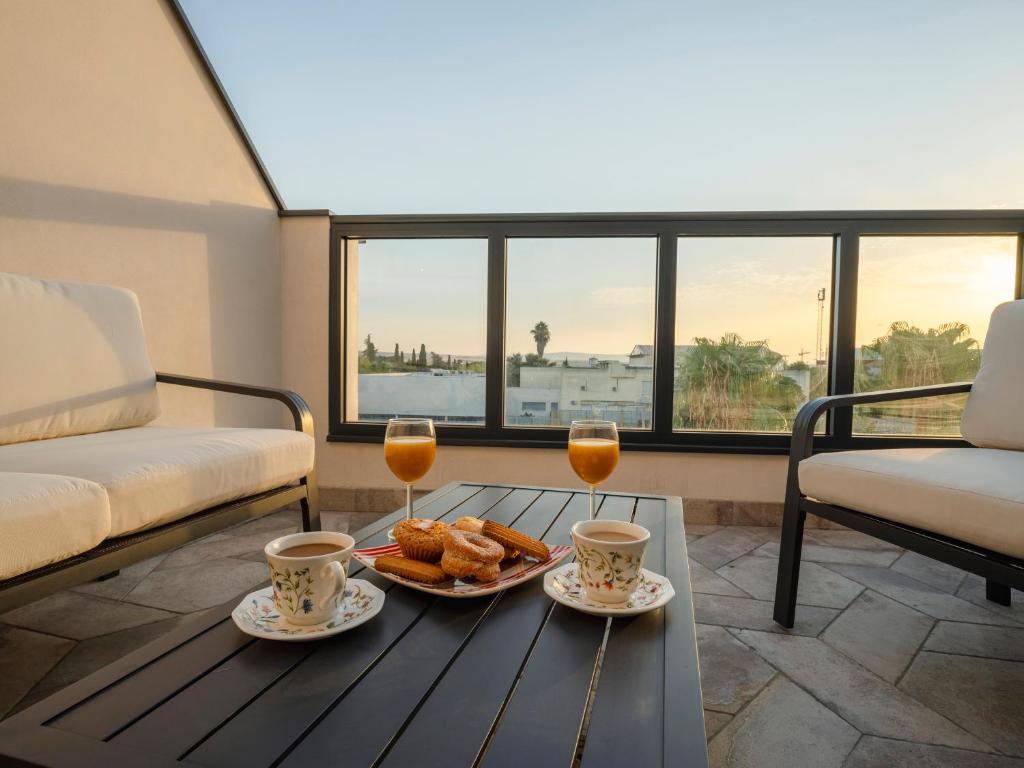 Apartamentos Rosa Velázquez في ماردة: طاولة قهوة مع كأسين من عصير البرتقال والحلويات