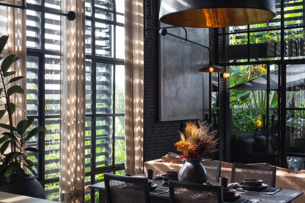 a dining room with a table and chairs and windows at The Bohemian Bali in Canggu