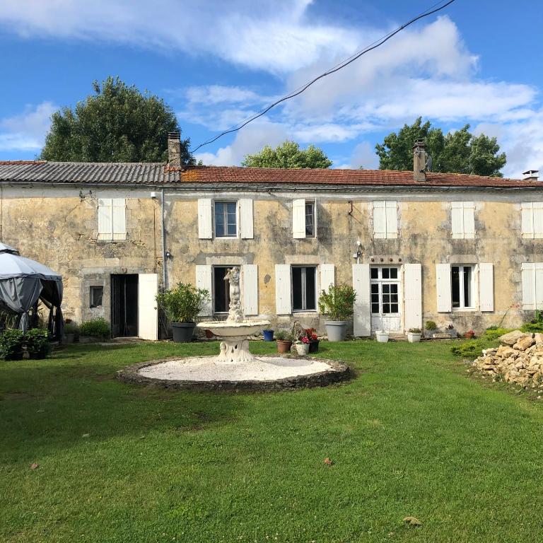 une ancienne maison en pierre avec une fontaine dans la cour dans l'établissement Les Geais, à Péré