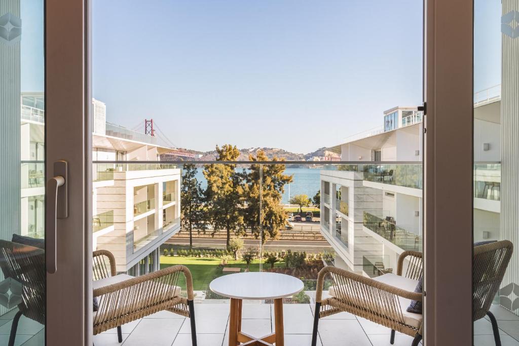 リスボンにあるHyatt Regency Lisbonのテーブルと椅子付きのアパートメントのバルコニーから景色を望めます。