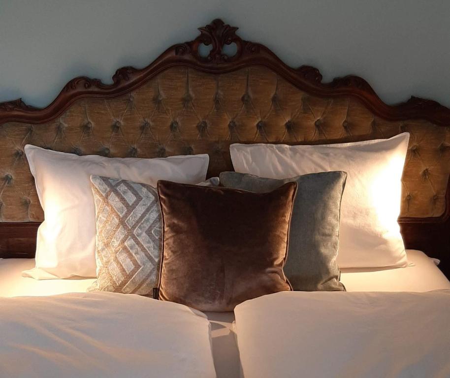 - un lit avec des oreillers blancs et une tête de lit en bois dans l'établissement LAnJA ihr besonderes Urlaubszuhause, à Lagundo