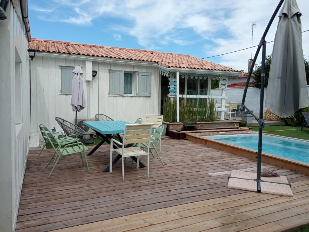 um deque com uma mesa e cadeiras e uma piscina em La cabane et sa cascade em Lège-Cap-Ferret