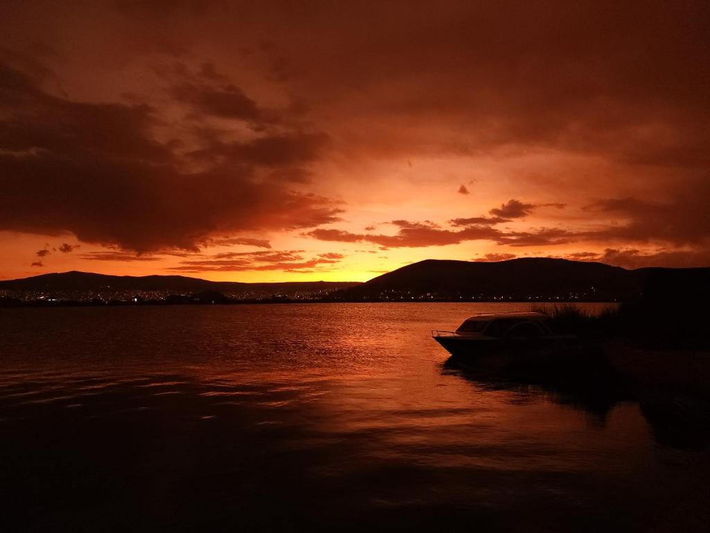 un barco en el agua con una puesta de sol en Hanan Pacha Lodge, en Puno