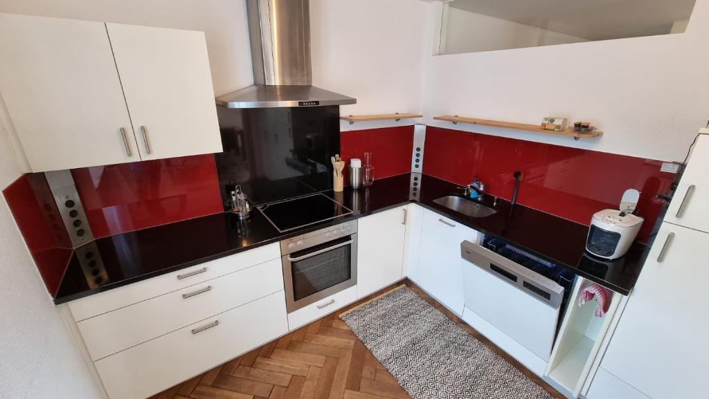 a small kitchen with red and white cabinets at Gasthof - Auszeit im Bad Diezlings - Adults only in Hörbranz