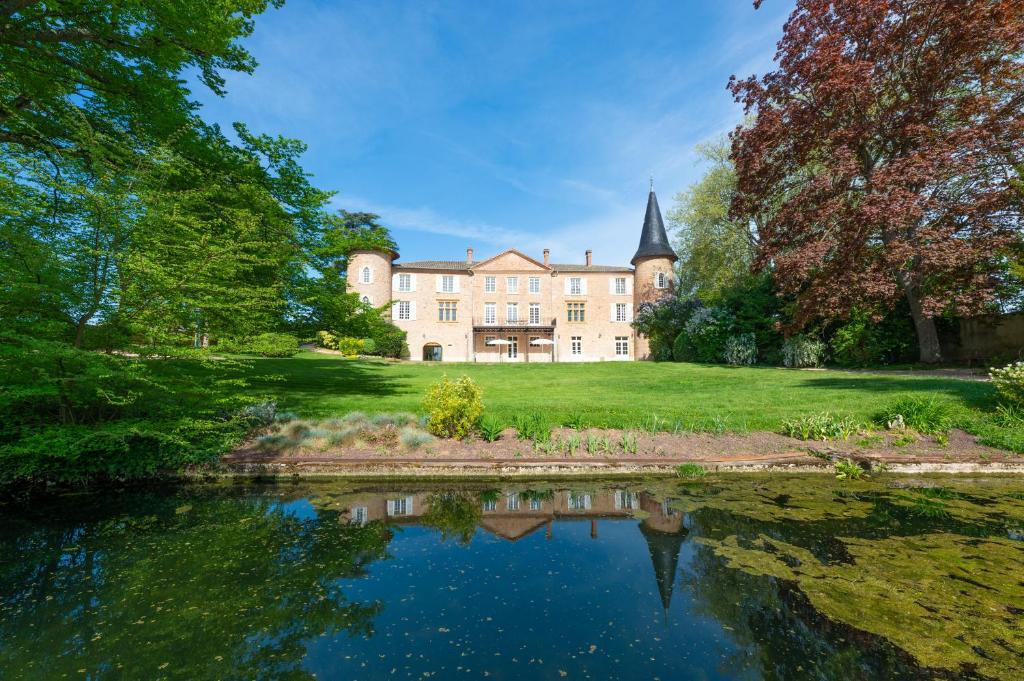 une grande maison avec un étang en face de celle-ci dans l'établissement Château de Champ-Renard, à Blacé