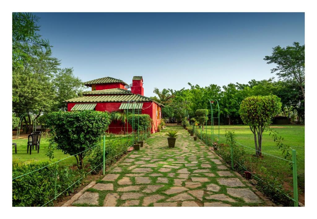 a fence with a red building in a park at An Authentic Village Farm in Jhānsi