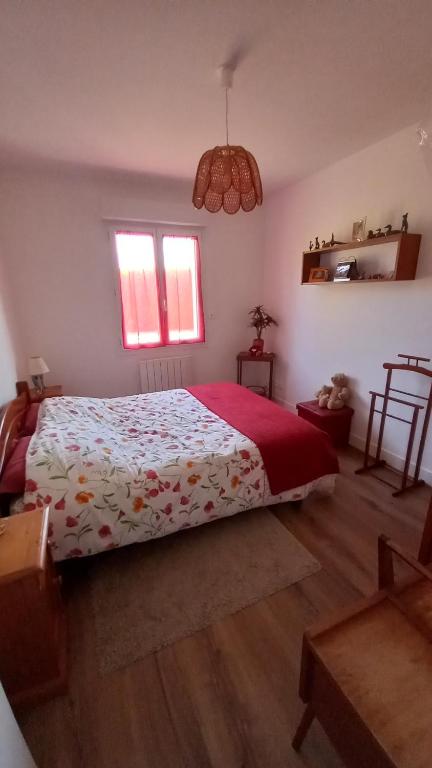 um quarto com uma cama grande e um cobertor vermelho em Chez Corinne em Colombelles