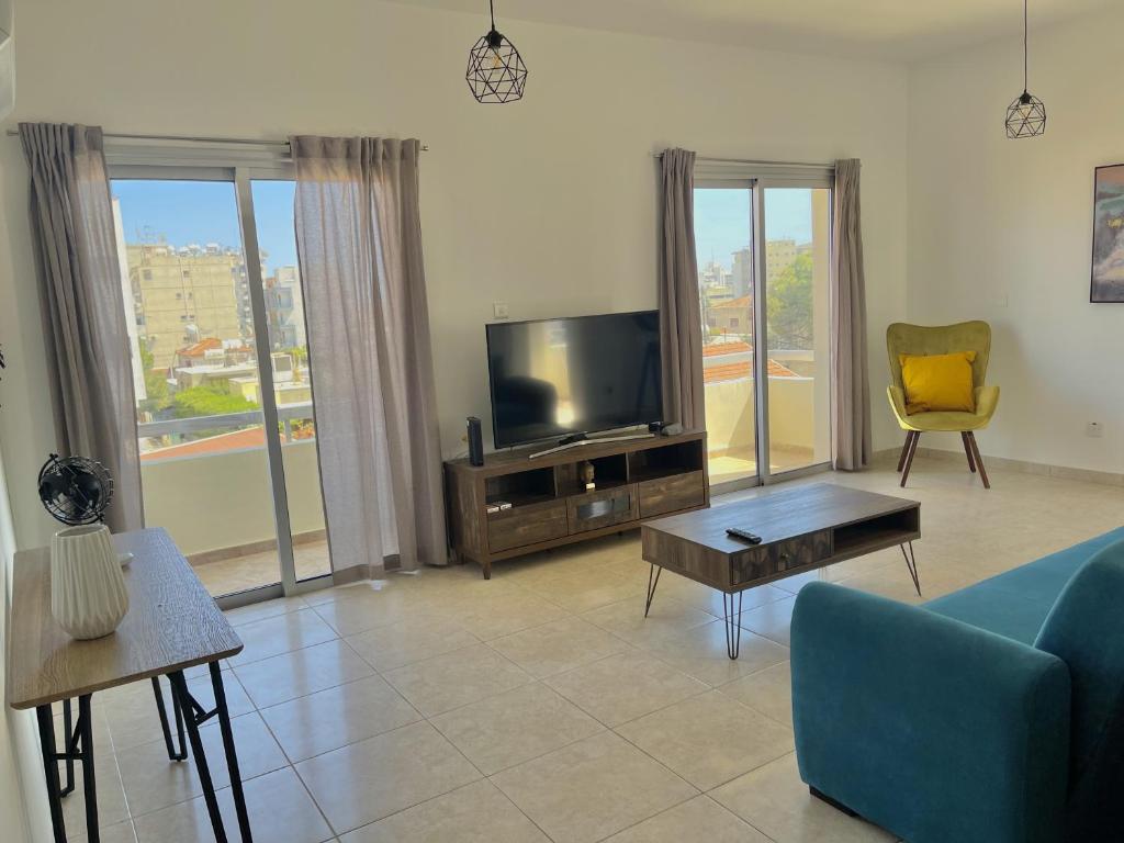 un salon avec un canapé bleu et une télévision dans l'établissement Urban Retreat - Your Ideal Getaway in Limassol, à Limassol