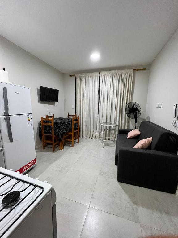 sala de estar con sofá negro y cocina en Apart Juncal en Corrientes