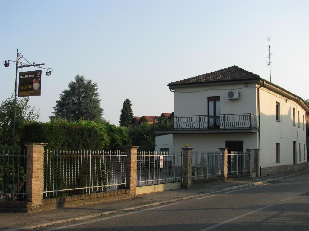 una casa blanca con una valla al lado de una calle en B&B Reginetta, en Casteggio