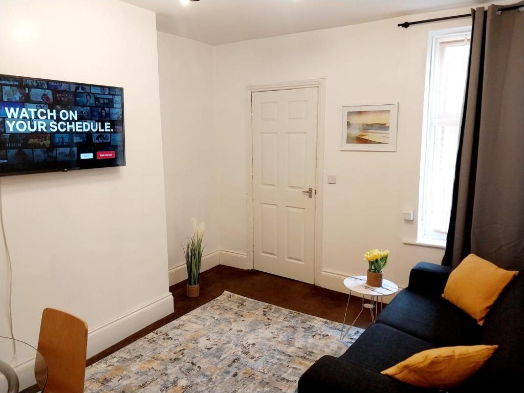 a living room with a couch and a tv on a wall at CityHost Apartments - Newcastle in Elswick