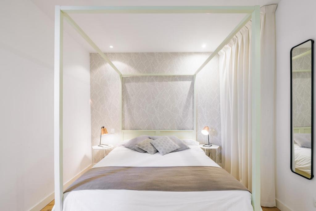 1 dormitorio blanco con 1 cama con dosel y 2 lámparas en mi casa en Madrid- spacious apartments Callao Gran Via, en Madrid
