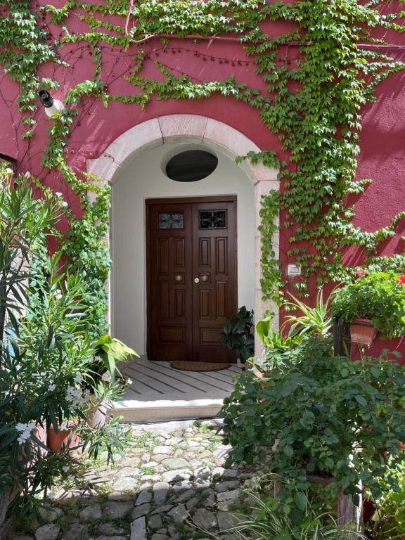 - un bâtiment rouge avec une porte en bois et du lierre dans l'établissement Borgo Vivo, à Calitri