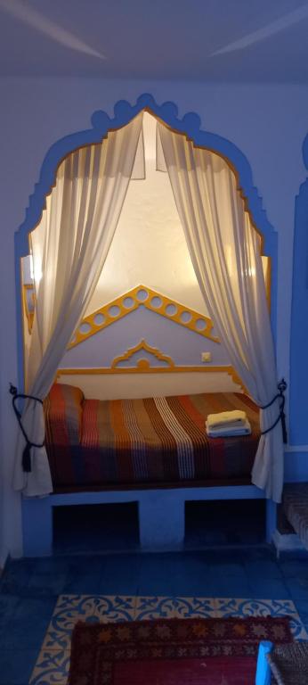 a bed with a canopy in a blue room at Hôtel Dar Terrae in Chefchaouen