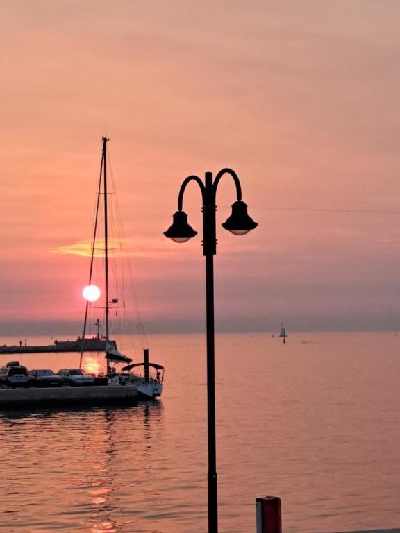 una luz de la calle y un barco en el agua al atardecer en Boat & breakfast, en Umag