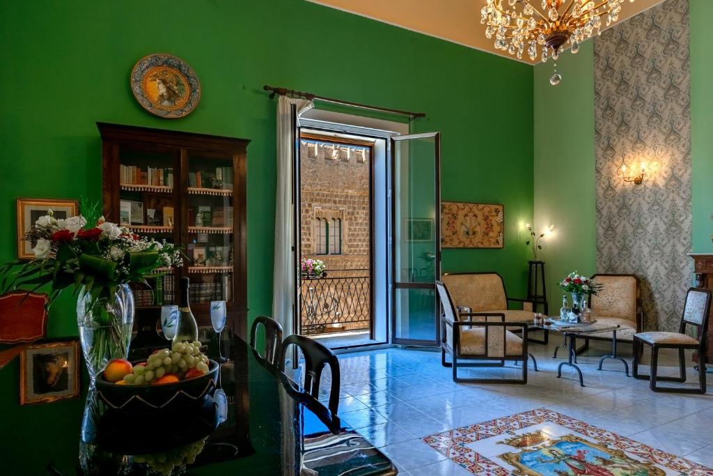 uma sala de estar com paredes verdes e uma mesa com uma taça de fruta em B&B TOMMASO FAZELLO SCIACCA Residenza artistica em Sciacca