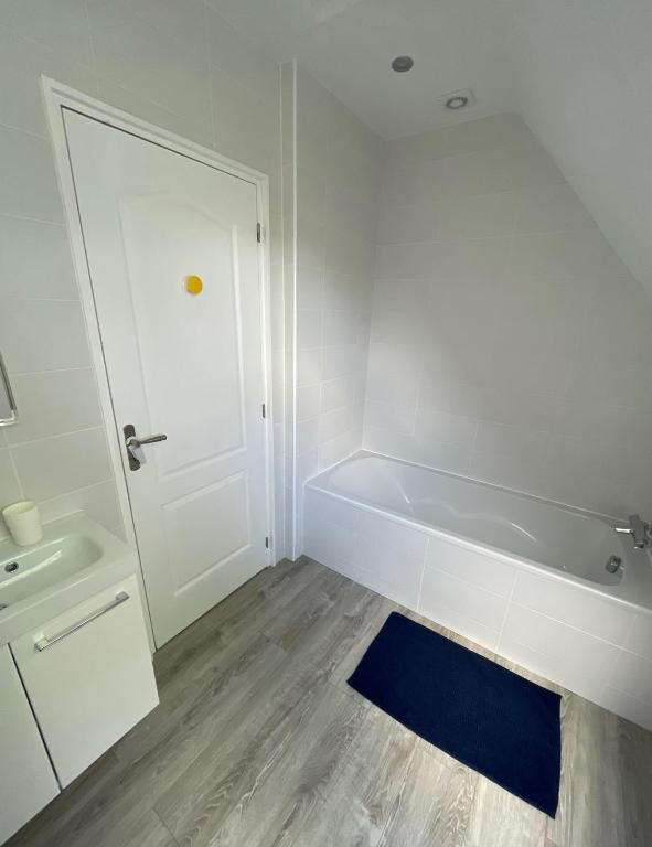 a white bathroom with a tub and a sink at Kerprimel in Saint-Thois