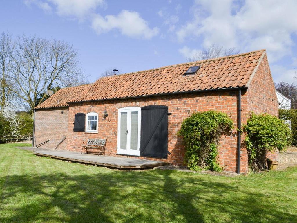 uma casa de tijolos vermelhos com uma porta branca e um quintal em The Shepherds Bothy em Tetford