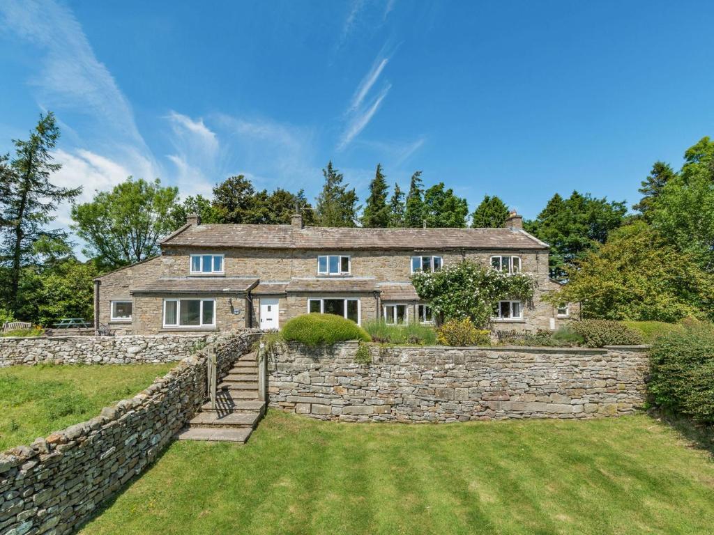 an exterior view of a stone house with a stone wall at Town Head Cottage in Carlton