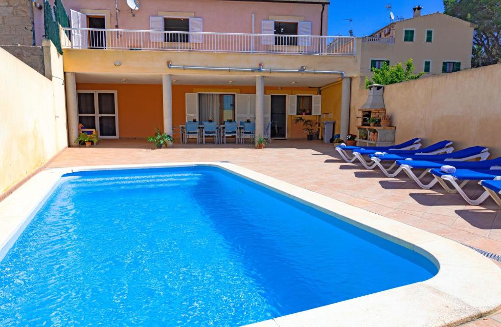 a swimming pool in front of a house with blue chairs at 039 Casa Marimar ETV8486 by Mallorca Charme in Muro