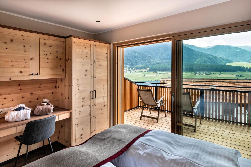 a bedroom with a bed and a balcony with a view at Silent Luxury Chalet LAIET in San Valentino alla Muta