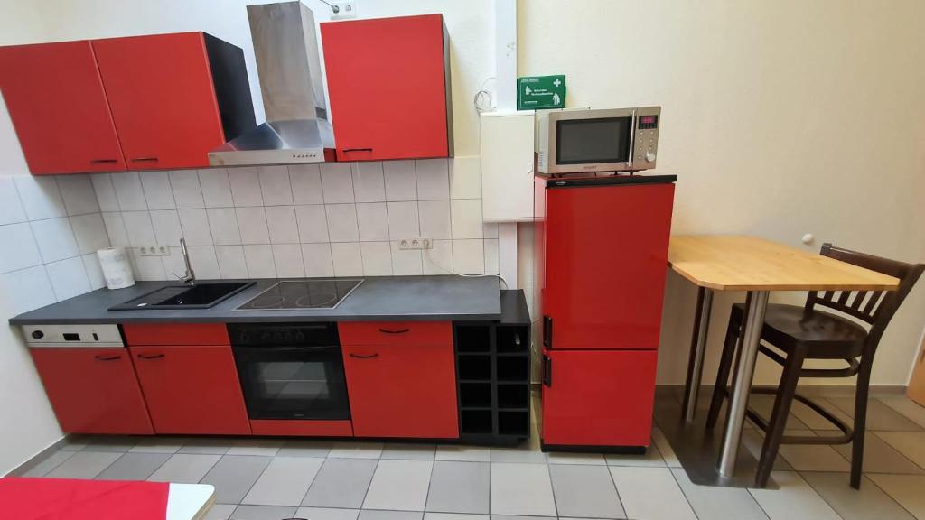 una pequeña cocina con armarios rojos y una mesa en Ferienwohnung am Ring en Baar