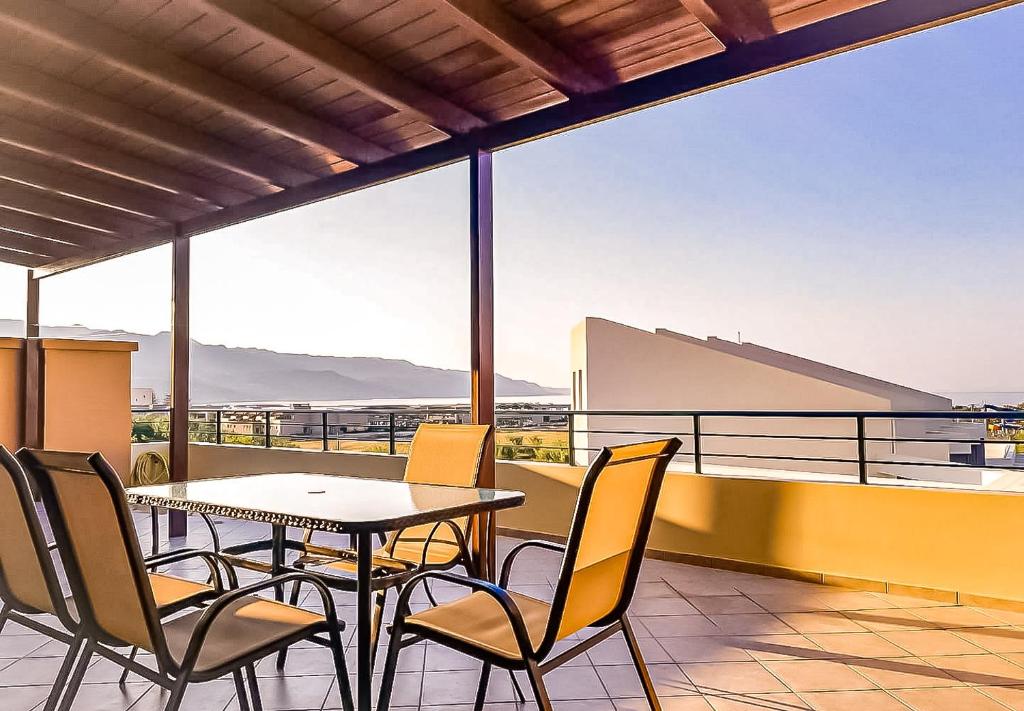 a table and chairs on a balcony with a view at Οικογενειακό διαμέρισμα 24χλμ από τα Χανιά in Ropanianá