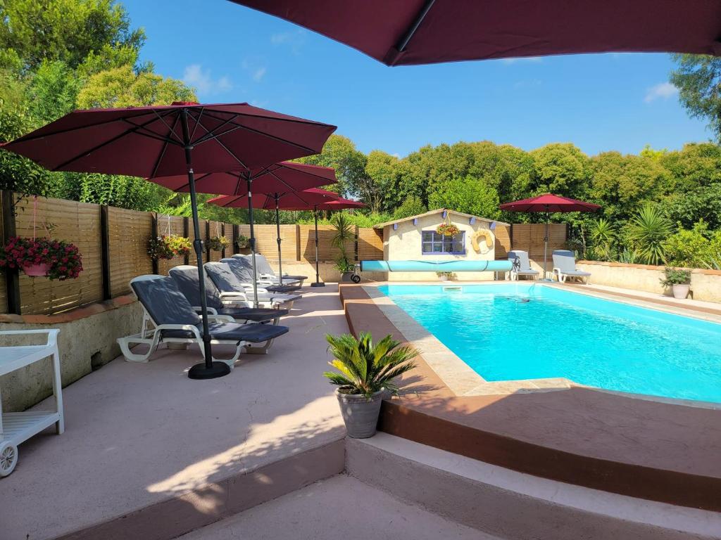 een zwembad met parasols en stoelen naast bij Mas d'Alivon in Arles