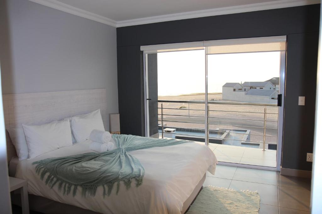 1 dormitorio con 1 cama y vistas a un balcón en Atlantic Dunes Unit 10, Self Catering en Rand Rifles