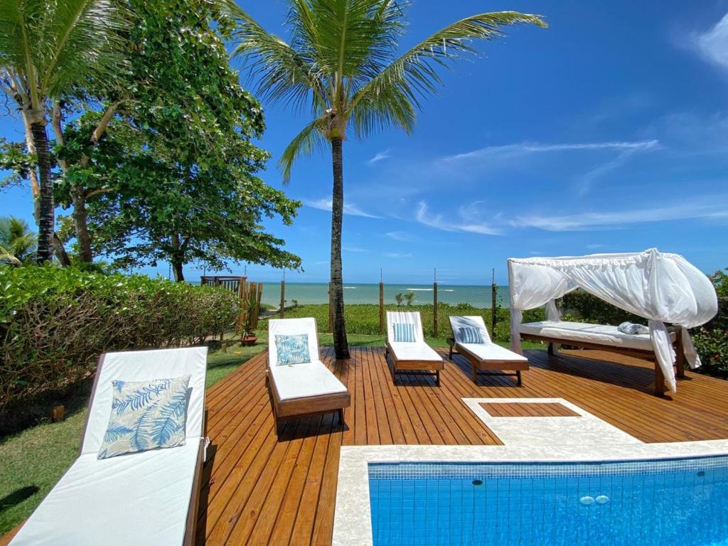 a deck with three lounge chairs and a swimming pool at Pè na Areia Arraial d'Ajuda Villa Cristian in Arraial d'Ajuda