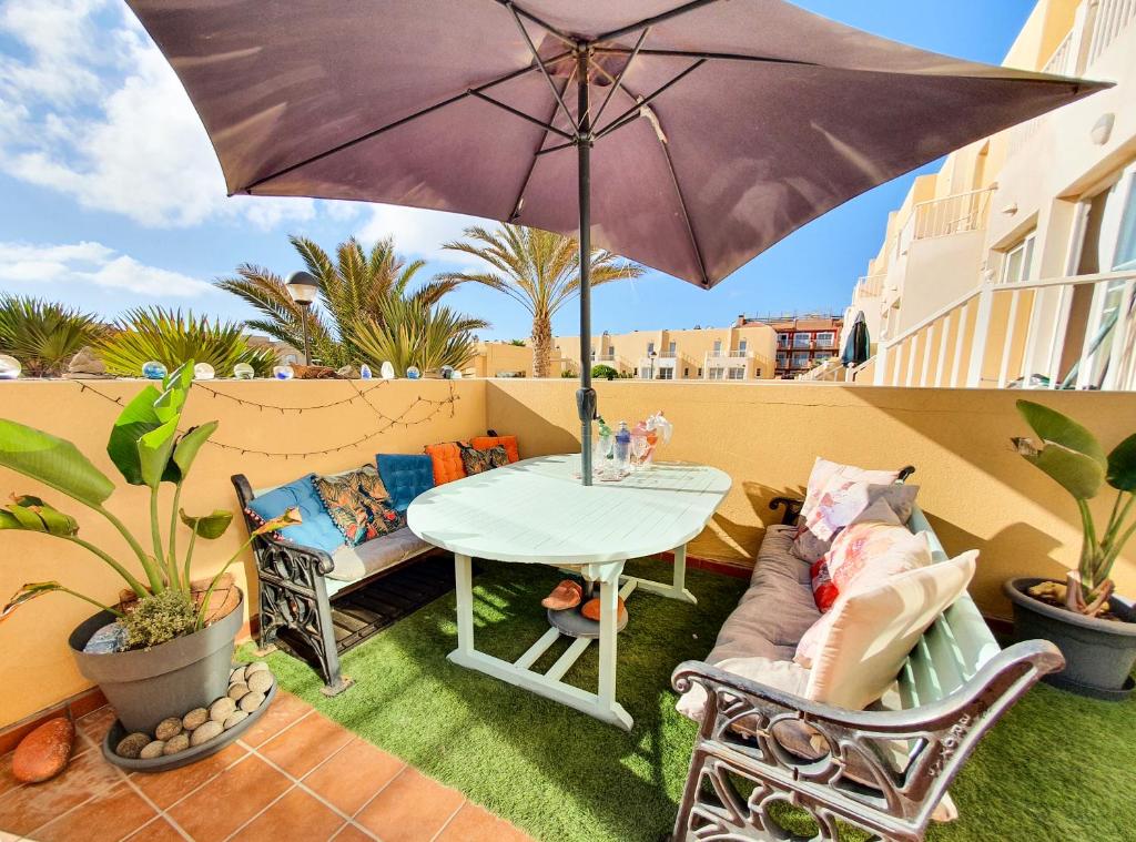 eine Terrasse mit einem Tisch, einem Sofa und einem Sonnenschirm in der Unterkunft Deluxe Home from Home in Caleta de Fuste in Caleta de Fuste