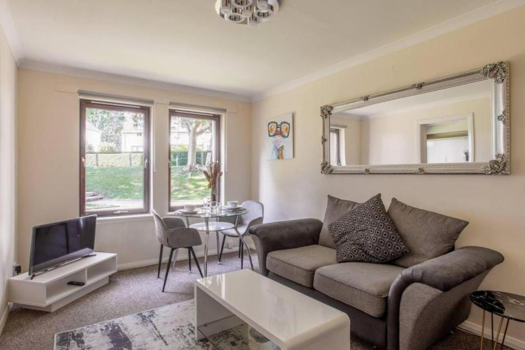 een woonkamer met een bank, een tv en een tafel bij The SUMMIT Apartment - Aberdeen City Centre - Perfect for Long and short Stay in Aberdeen