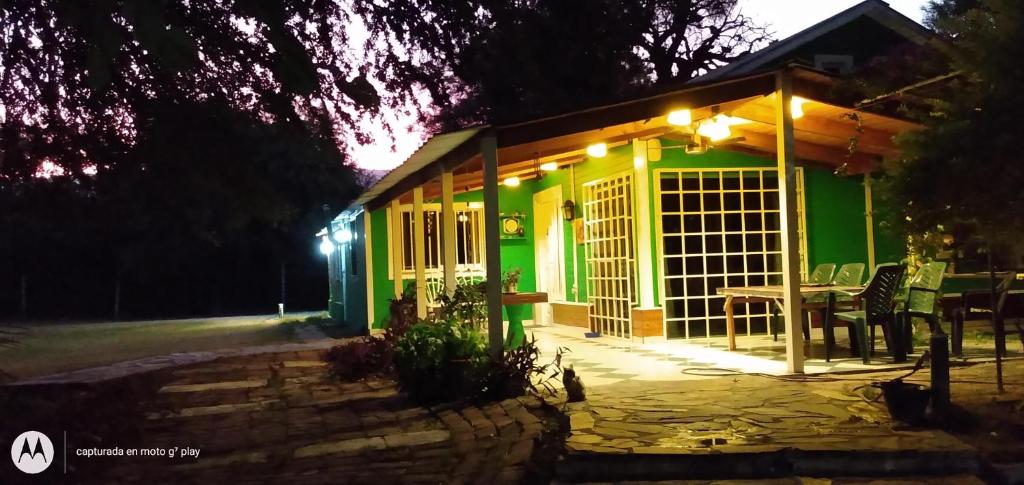 une maison verte avec une table devant elle la nuit dans l'établissement Catamarca Cabañas Star, à San Isidro