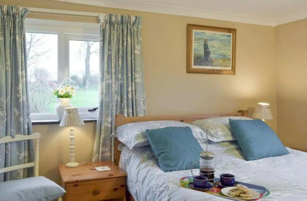 a bedroom with a bed with a tray of food on it at Broadhaven Cottage, Freshwater East, Pembs in Pembroke