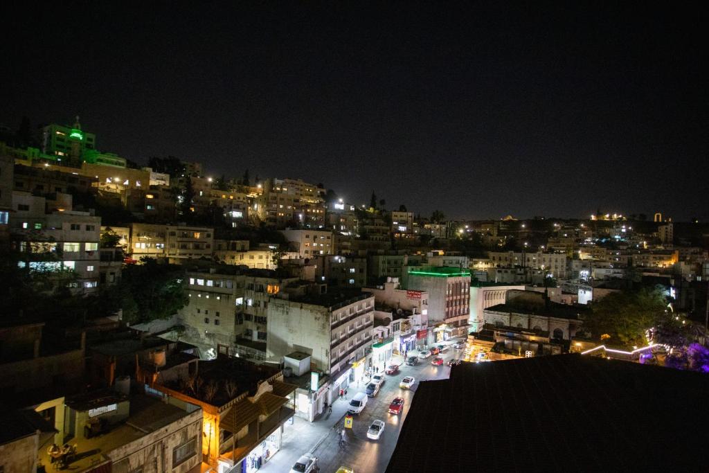 a city lit up at night with cars on the street at Hotel Philosophy in Amman