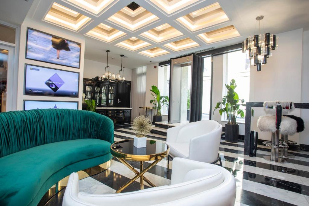 Hotel Philosophy في عمّان: غرفة معيشة مع أريكة خضراء وكراسي بيضاء