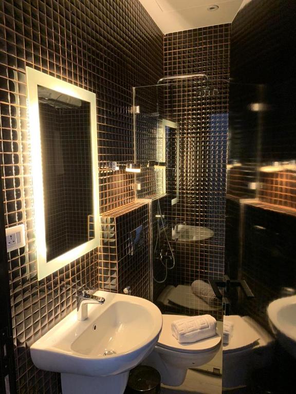 a bathroom with a sink and a toilet and a mirror at Hotel Philosophy in Amman