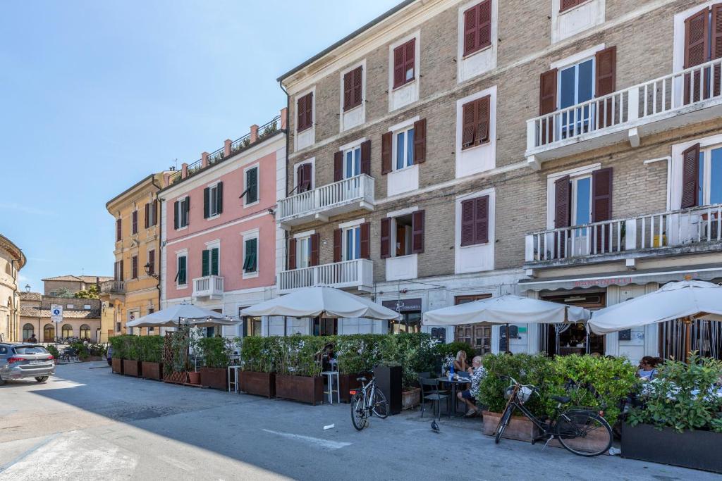 una strada con tavoli e ombrelloni di fronte a un edificio di La Romantica camere e wellness a Senigallia