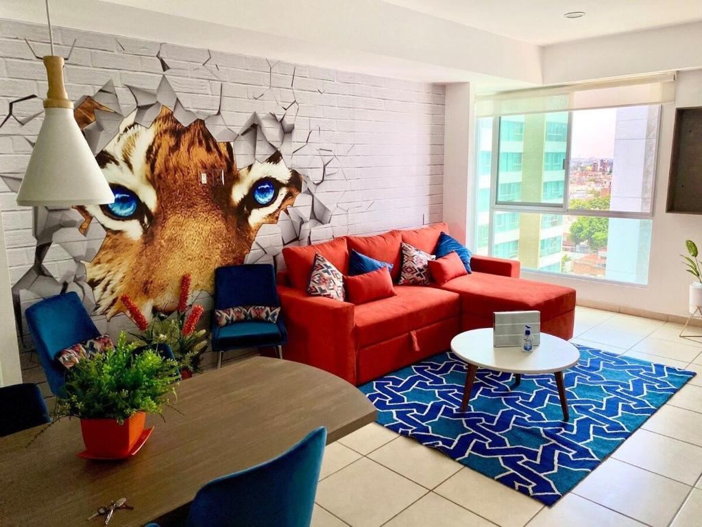 a living room with a red couch and a wall with eyes at Diseño Único Con 2 Recámaras, Alberca Y Gimnasio in Guadalajara