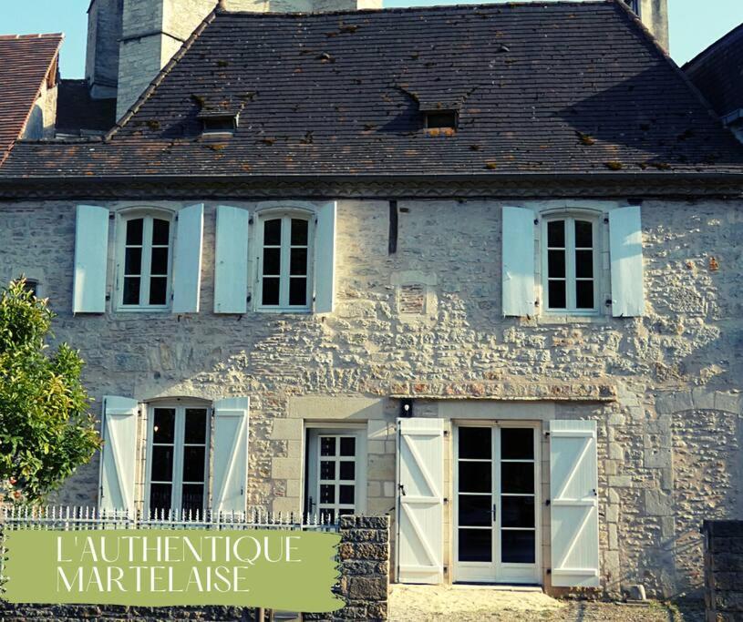 a building with white doors and a sign in front of it at L'authentique Martelaise PISCINE CHAUFFEE in Martel