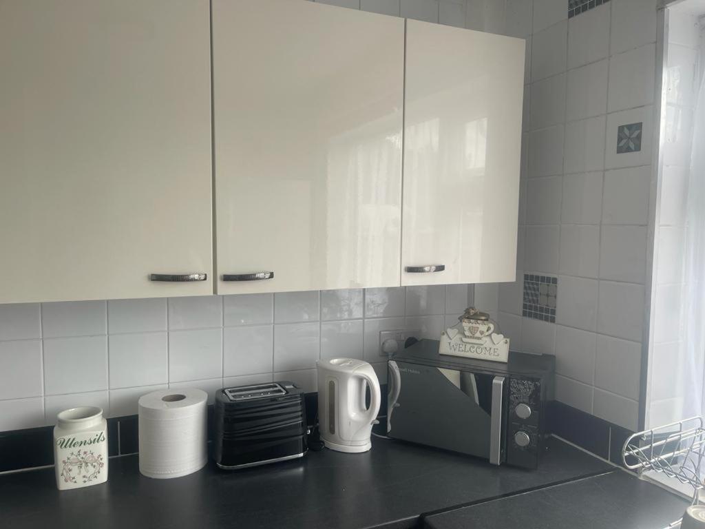 a kitchen with white cabinets and a counter top at Beautiful 2-bedroom in Grays close to Lakeside in Grays Thurrock