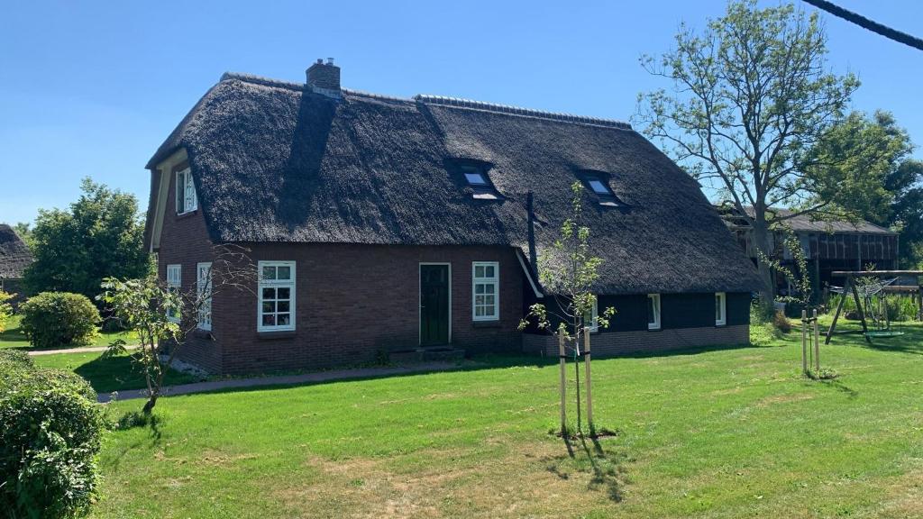 una casa antigua con techo de paja en un patio en Bed en Boomgaard, en Giethoorn